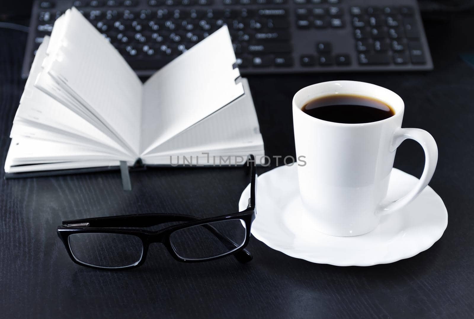 Business Office scene, laptop and notebook with coffee on black desk