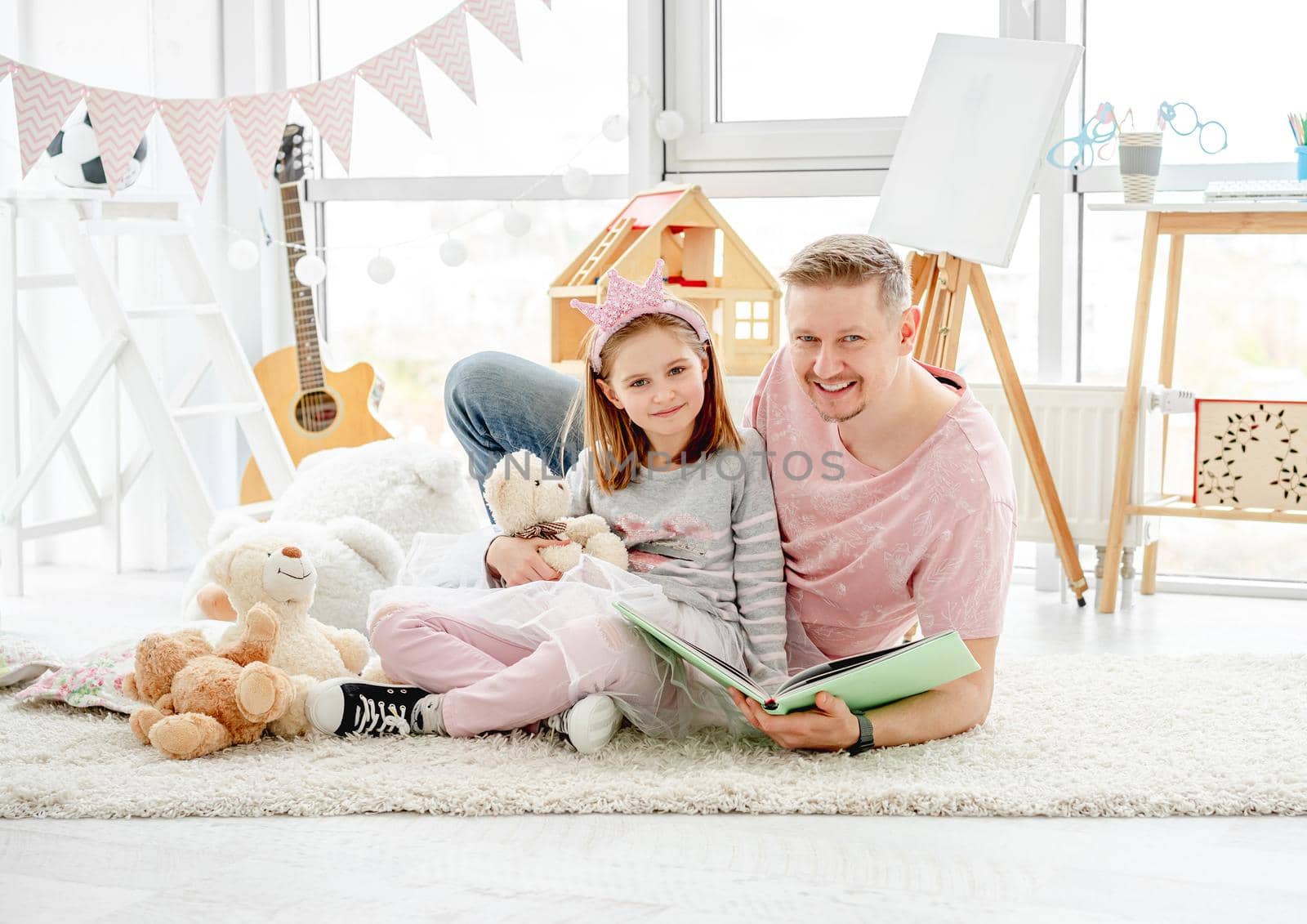 Cute little daughter with happy father reading book