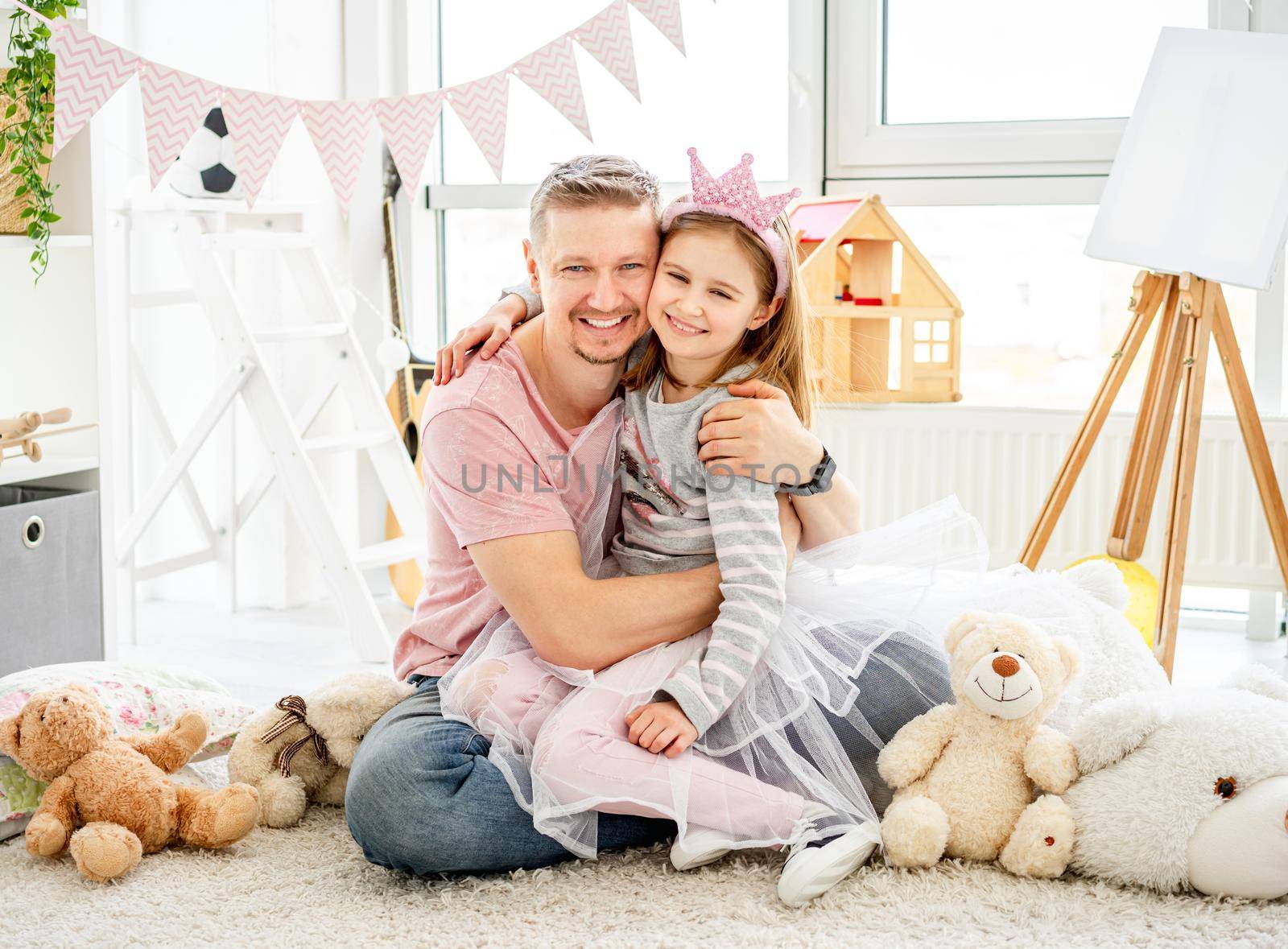 Happy father hugging with smiling daughter in children's room