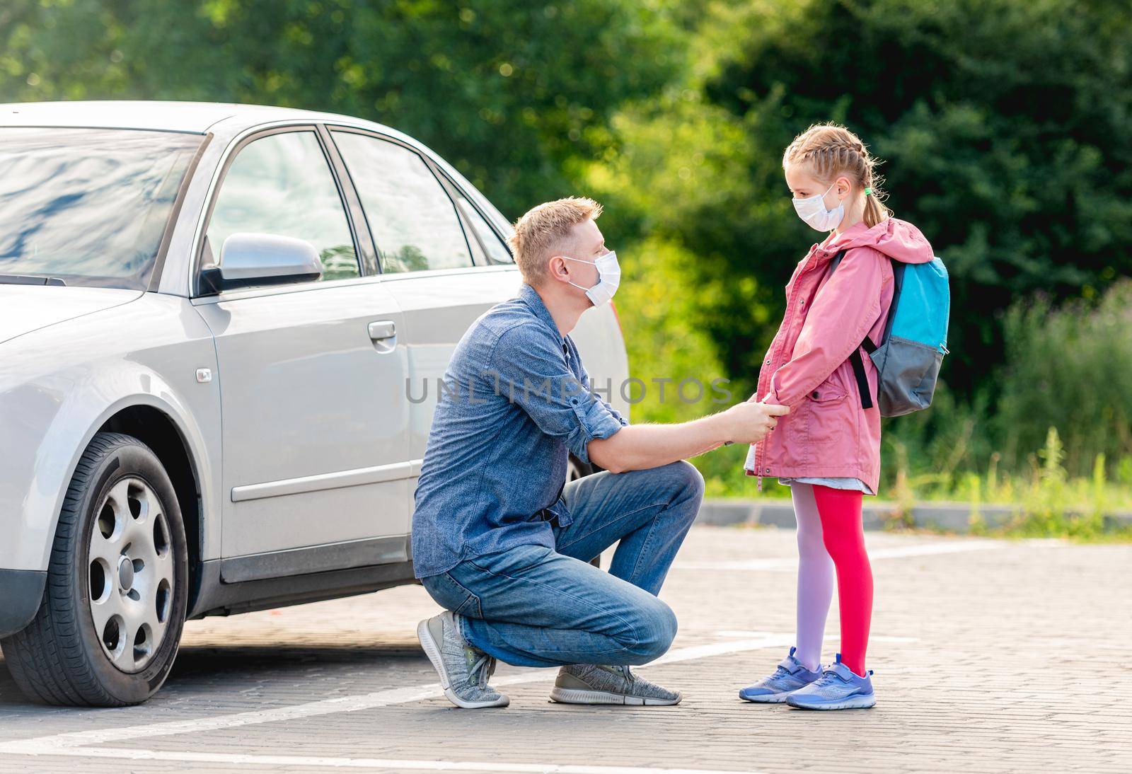 Father leading little girl back to school wearing medical masks