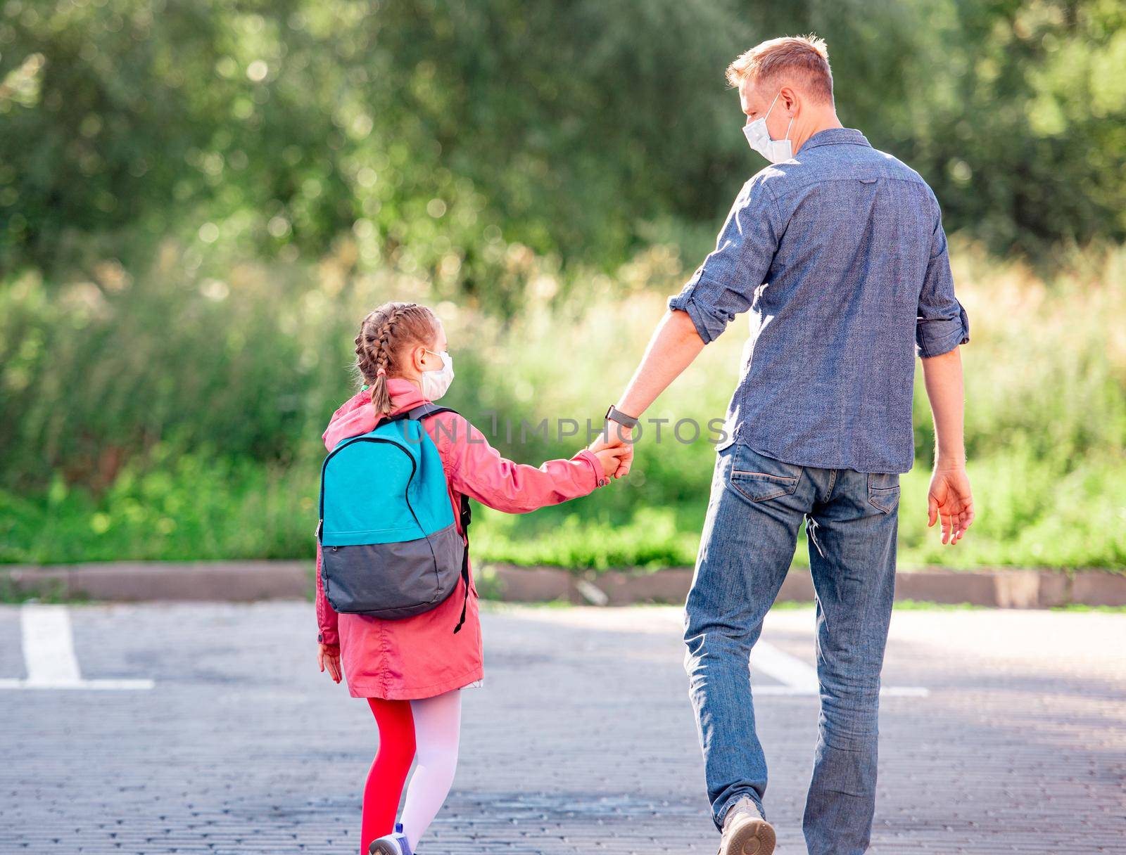 Daughter walking with father holding hands after school during coronavirus pandemic