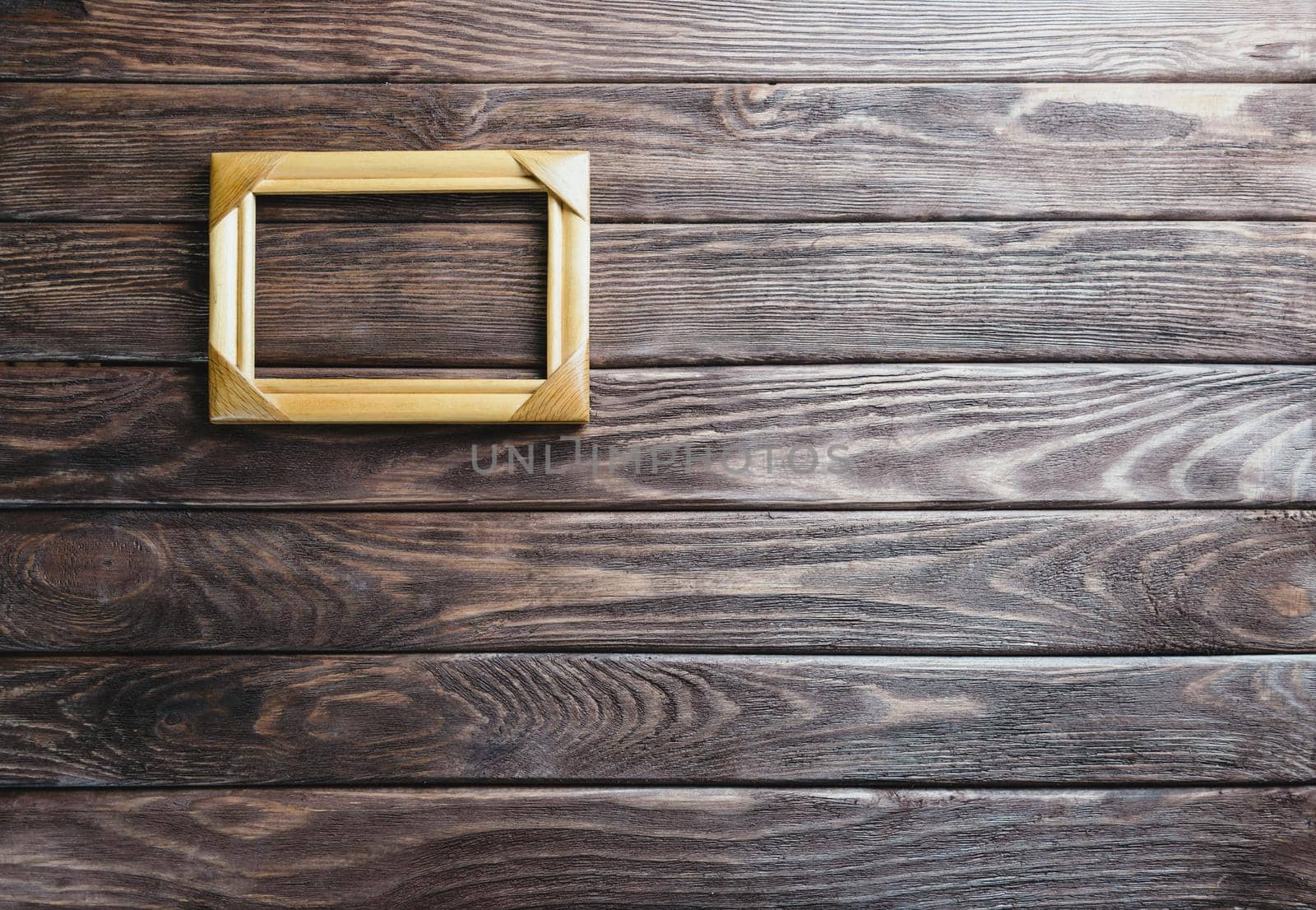 Empty square wooden frame on a dark background, top view. Copy-space.