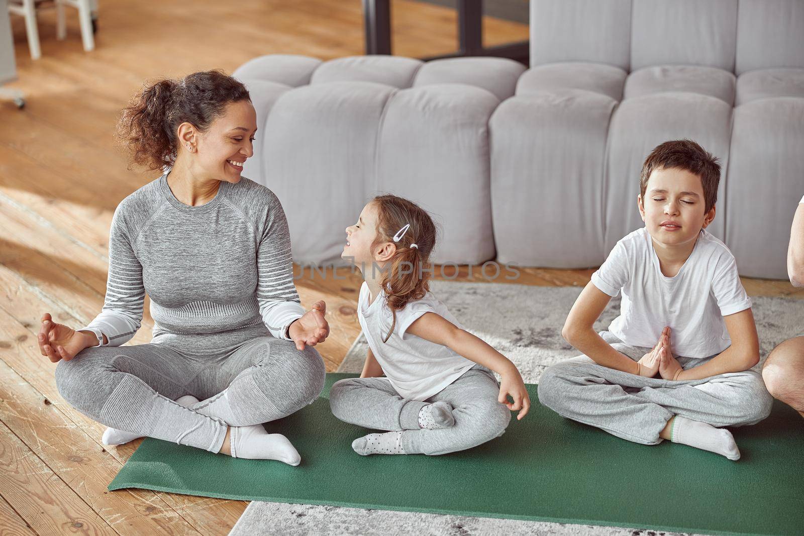 Top view of cheerful girl having fun with mom while boy is doing meditation with father