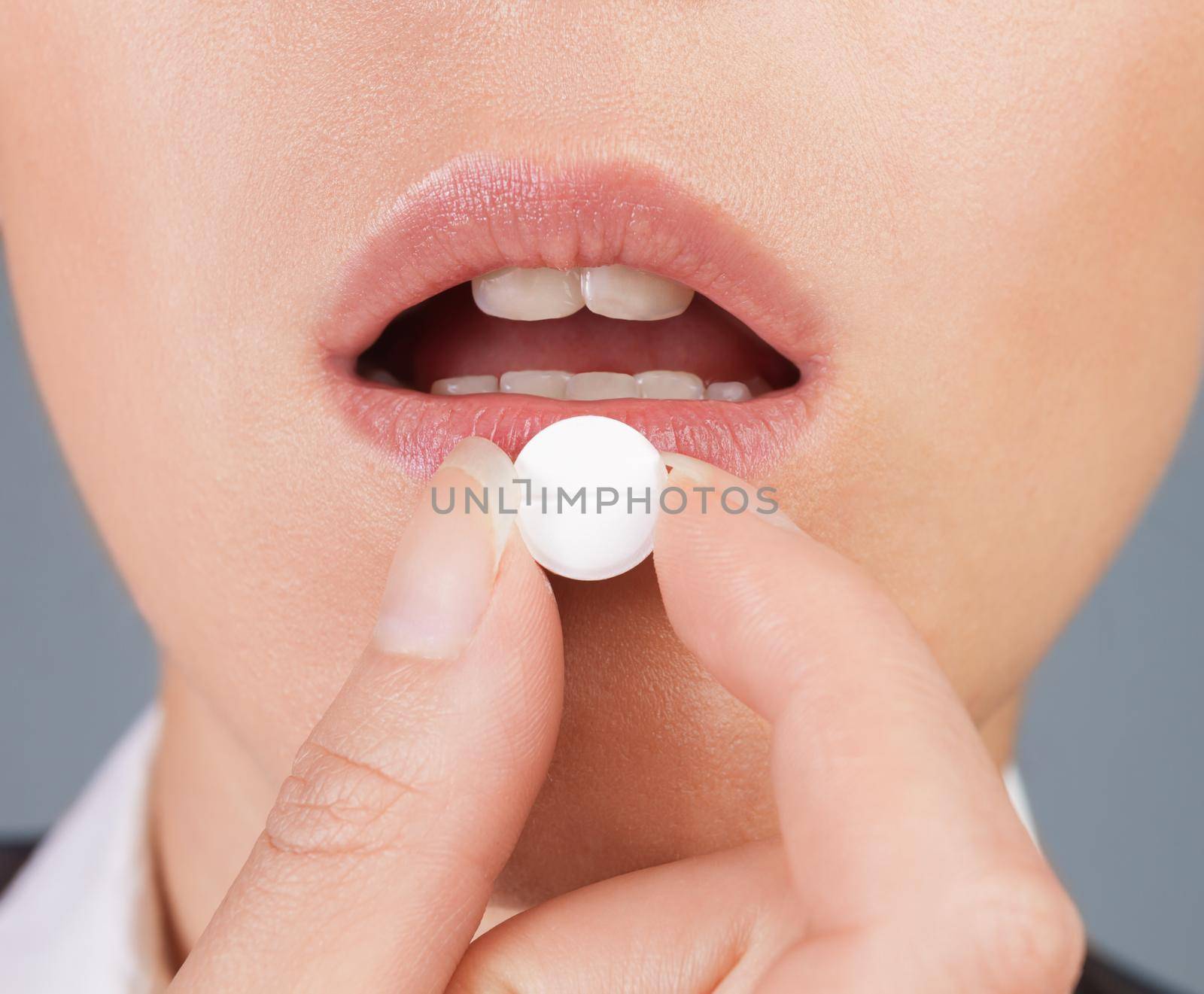 Round white pill is on the lower lip, close-up