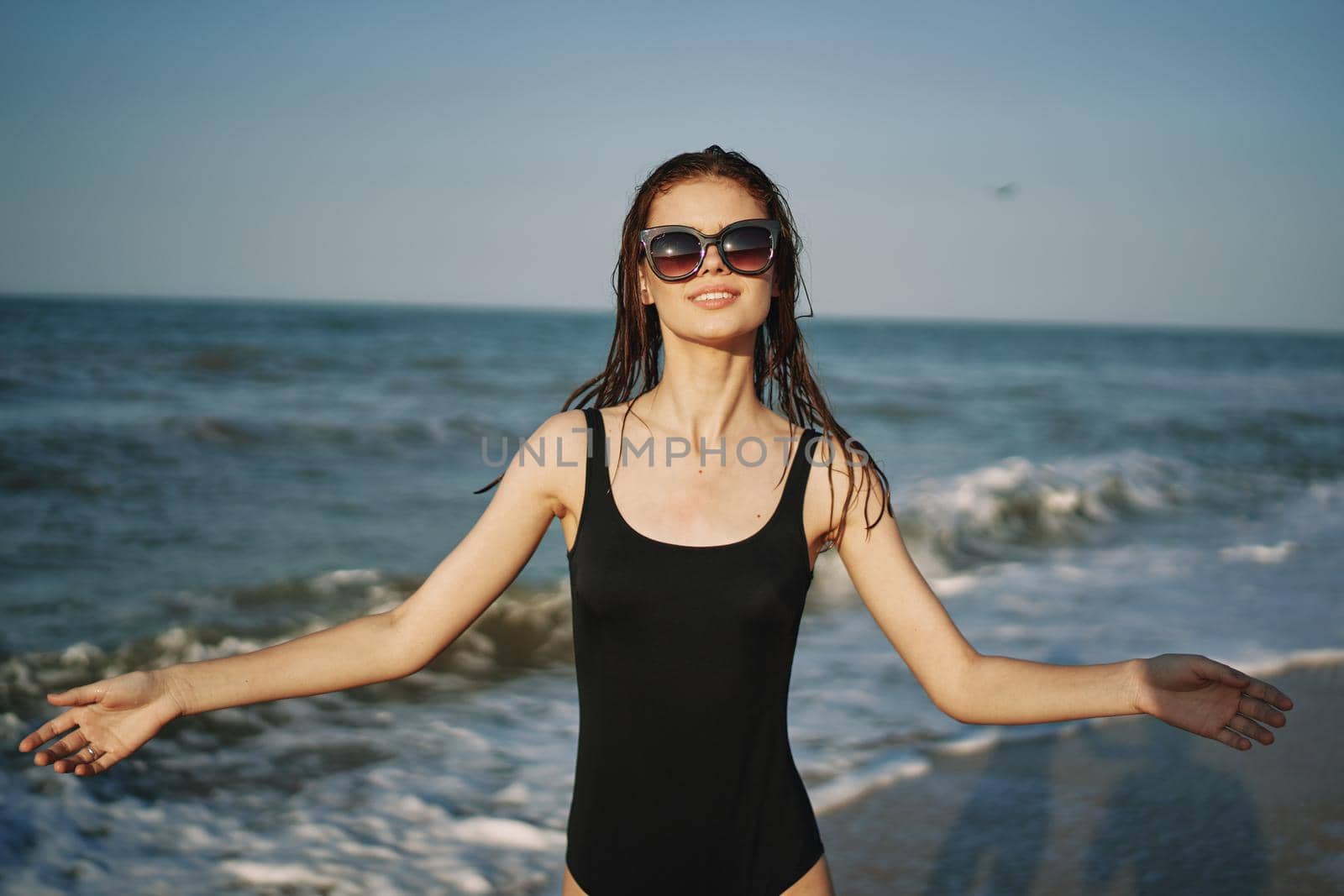 cheerful woman in black swimsuit sunglasses ocean travel. High quality photo