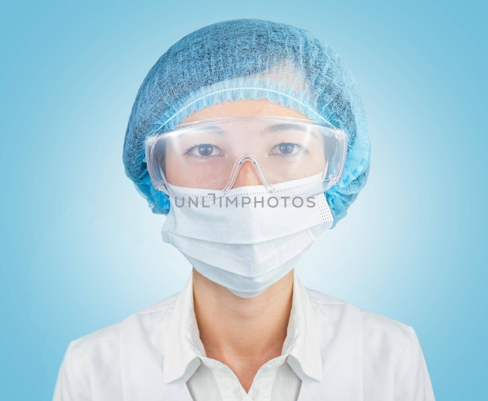 Portrait of female surgeon in cap, glasses and mask on a blue background