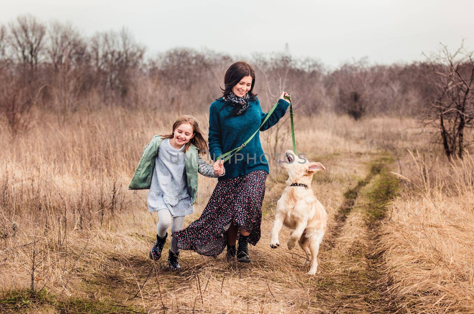 Playful dog walking with girl and woman outside