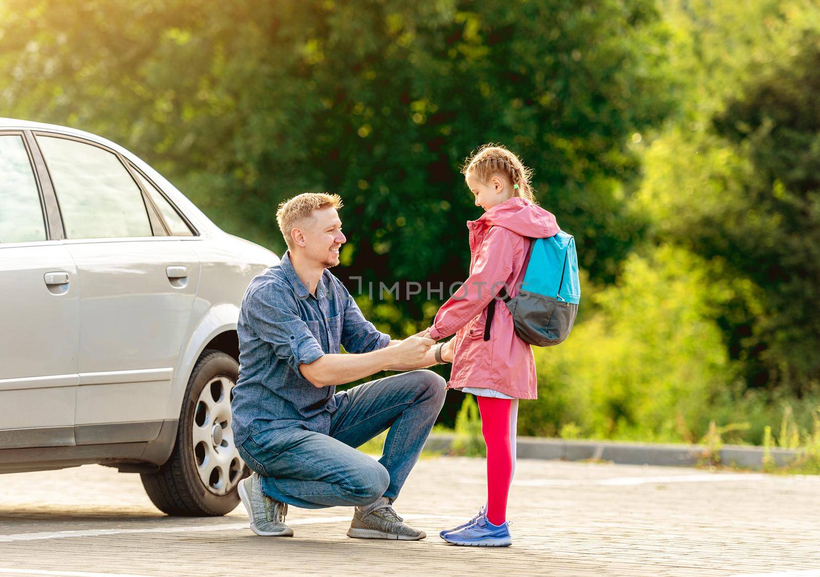 Father meeting little school girl after classes on parking