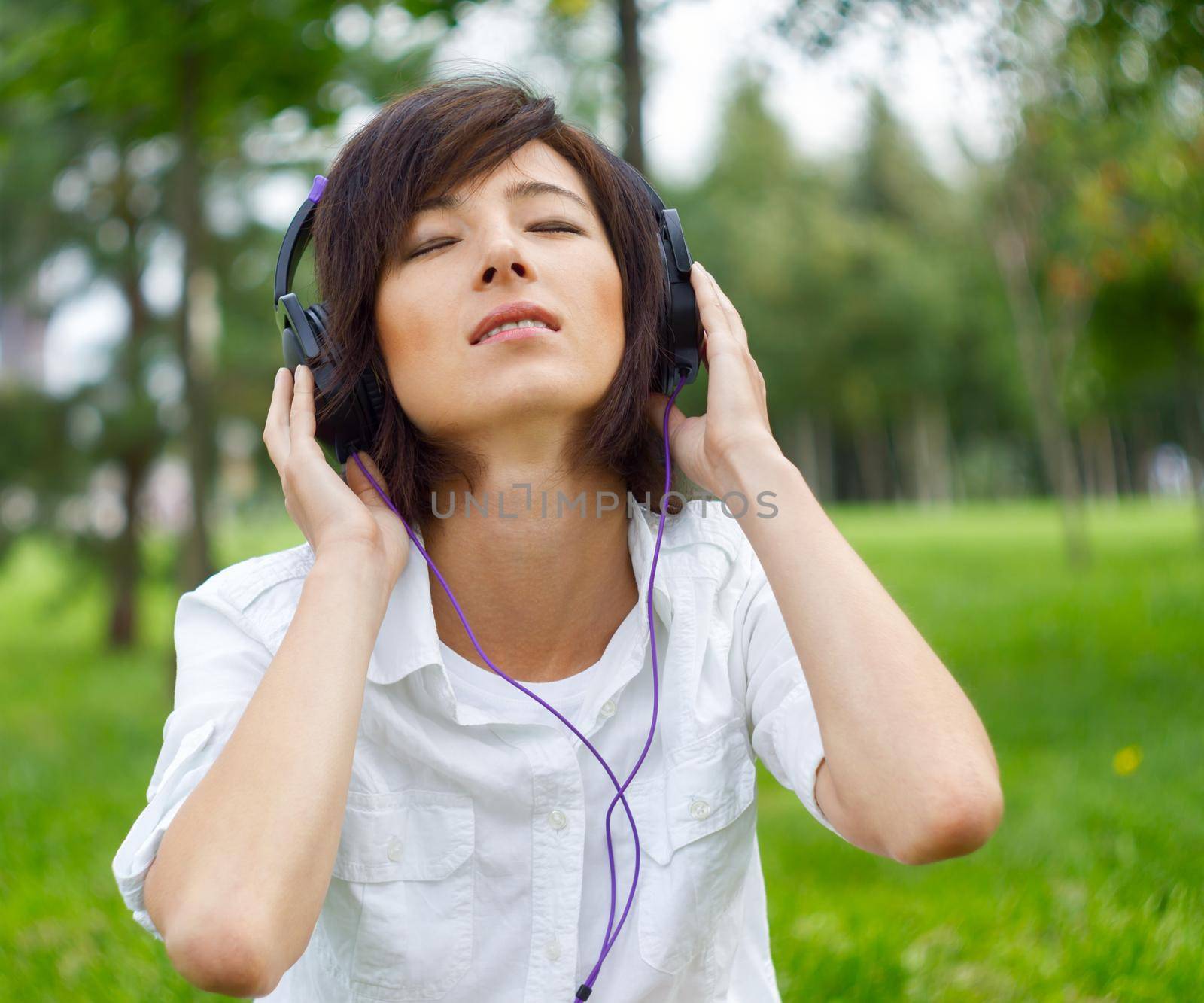 Beautiful young woman listening music in the park