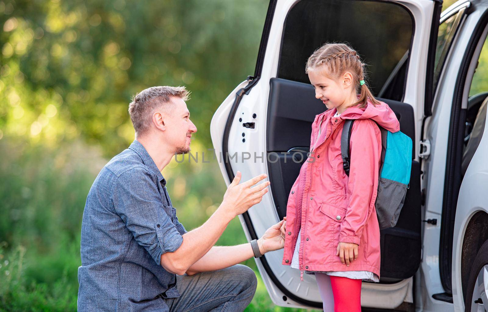 Father meeting little school girl after classes on parking