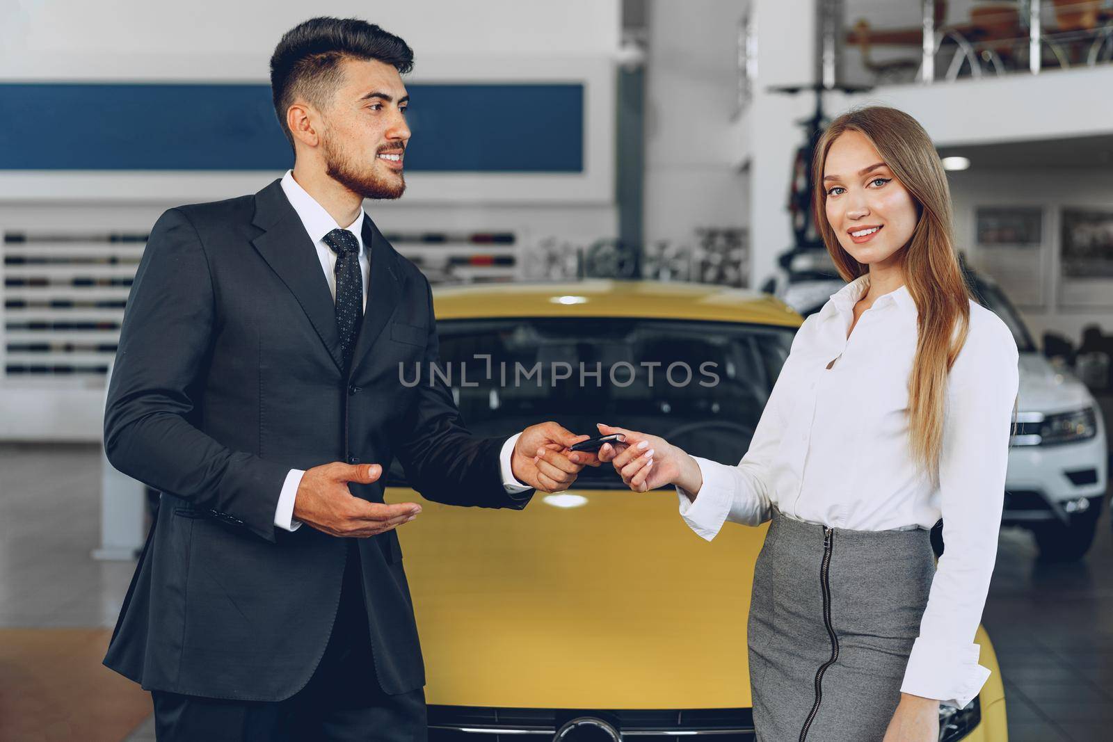 Young attractive woman buying a new car in car salon close up