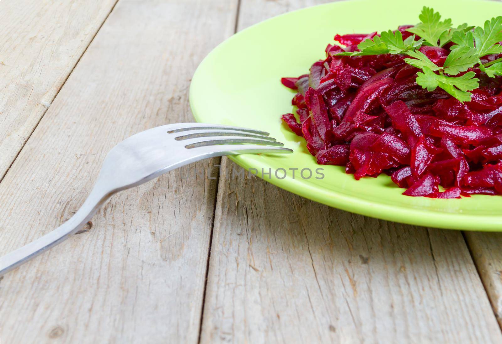 Beet salad with parsley on a green plate, side view