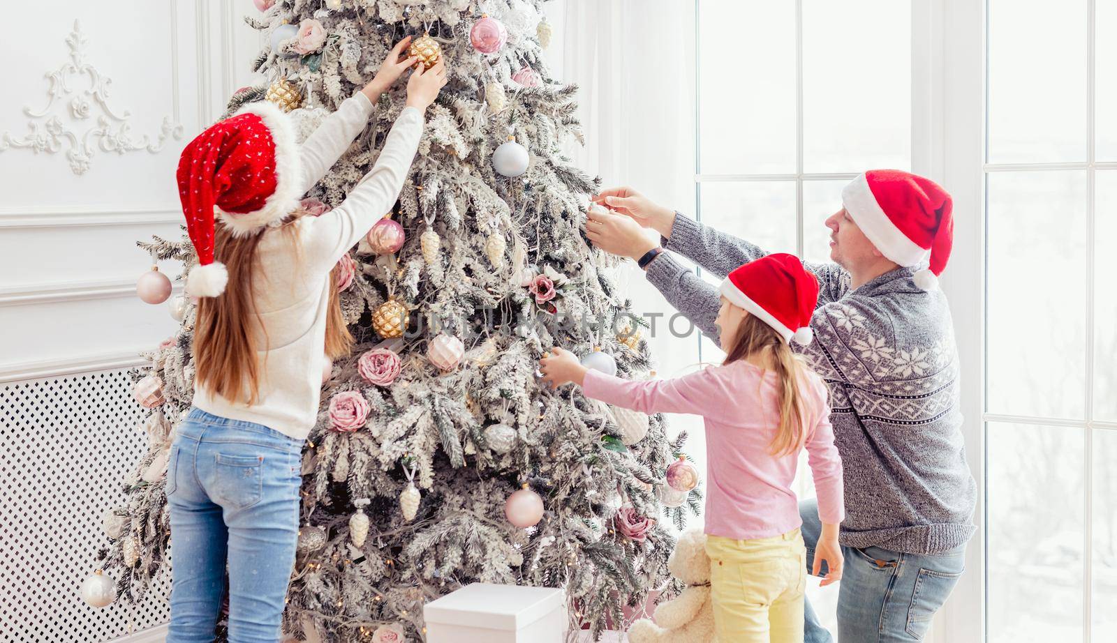 Father and daughters decorating christmas tree by tan4ikk1