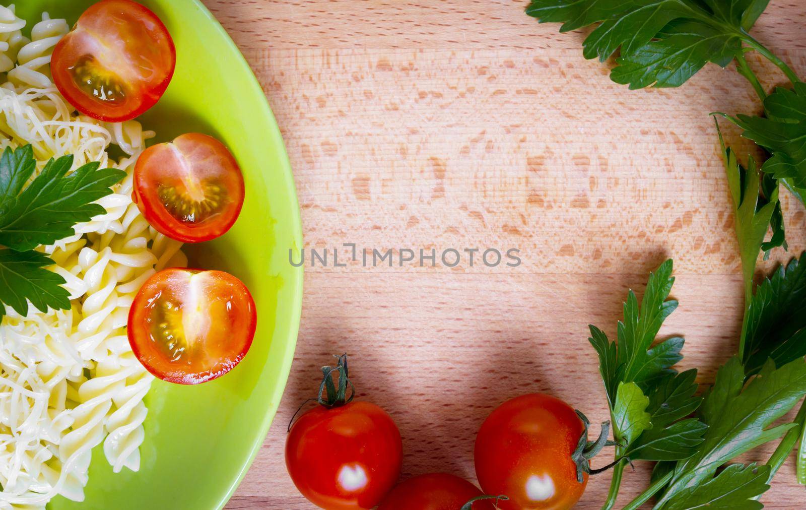 Dish of macaroni with cheese, tomatoes on the green plate, side top