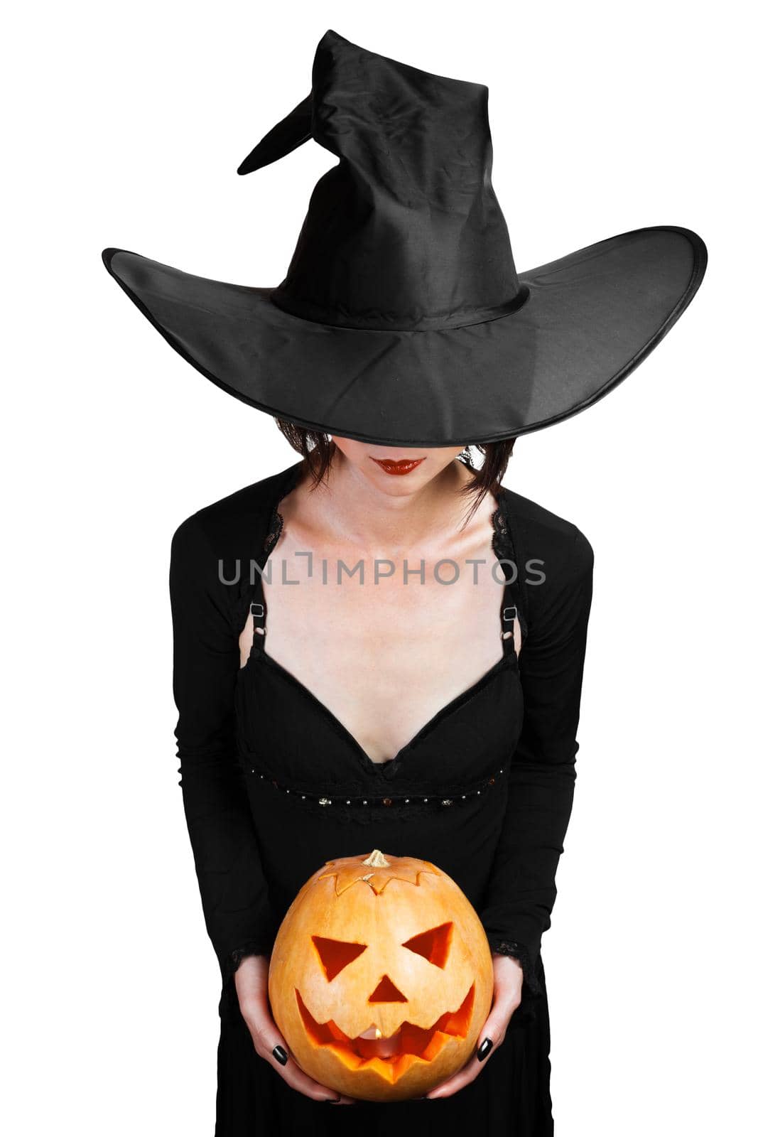 Halloween beautiful witch holding carved pumpkin on a white background