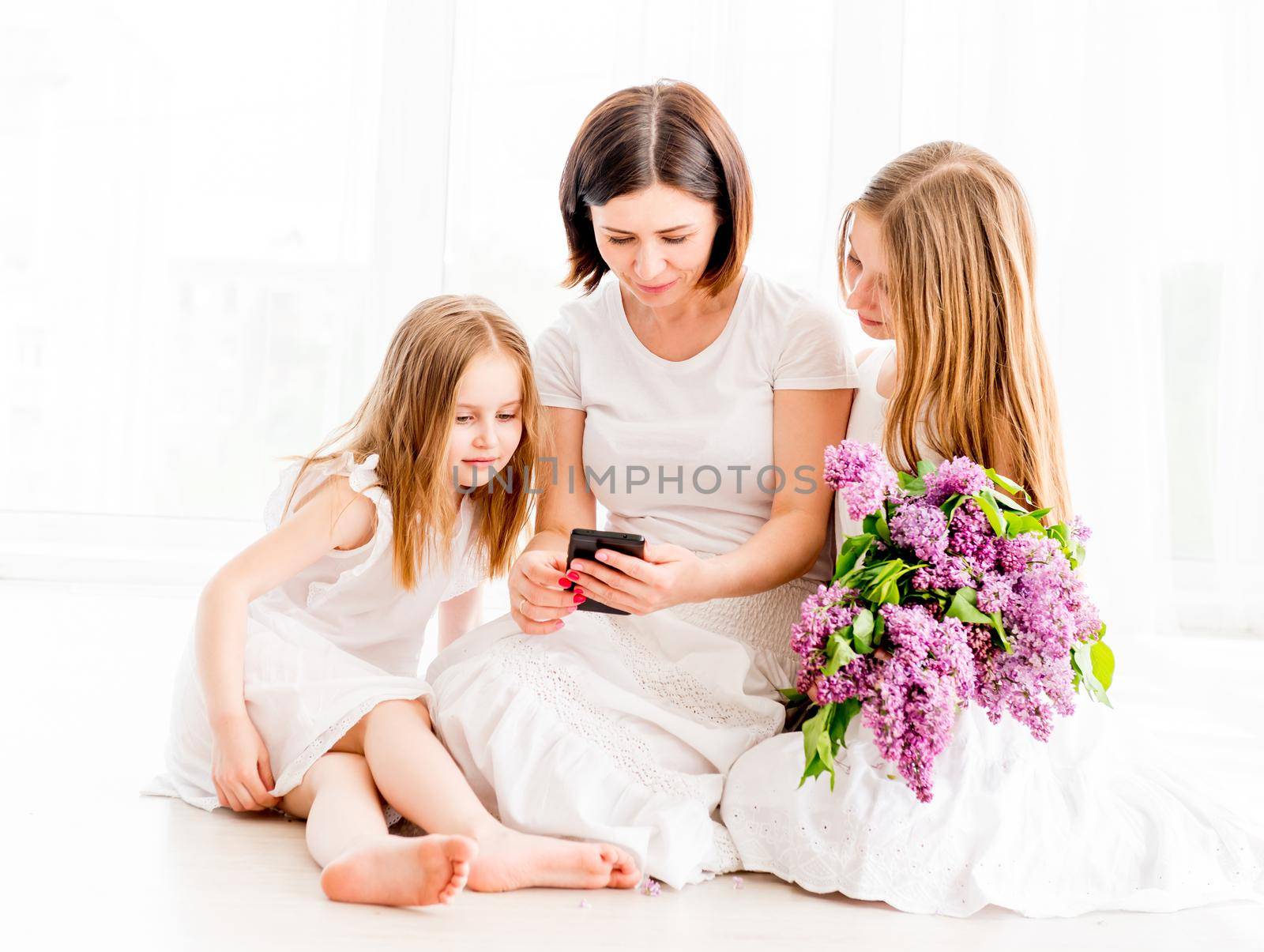 Mother with daughters looking at smartphone by tan4ikk1