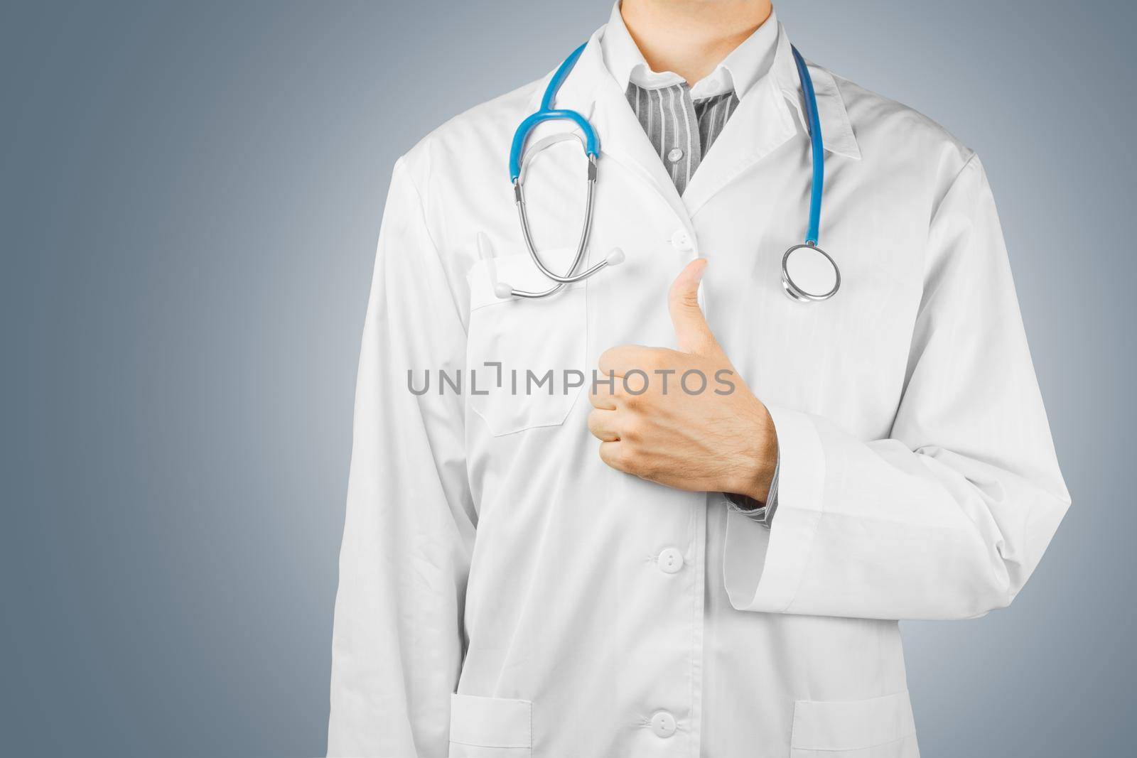 Male doctor shows gesture thumbs up on a gray background, space for text