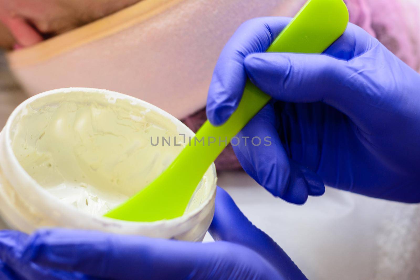 The beautician mixes the golden mask before applying on the face, mixing the mask in a bowl. new