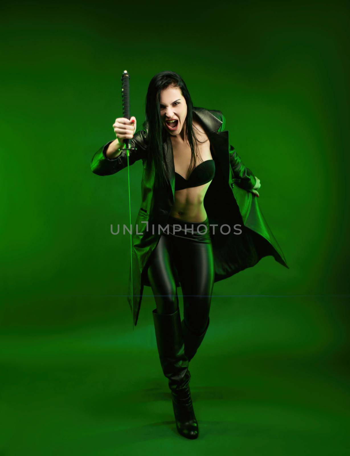 the slender woman in a black leather katana cloak on a green background