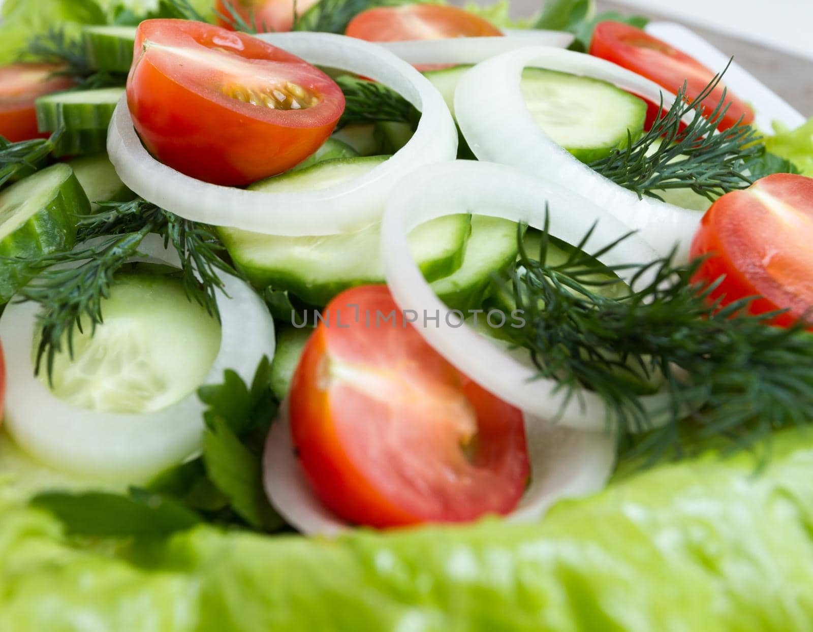 Salad of cucumbers, tomatoes and greens, close up