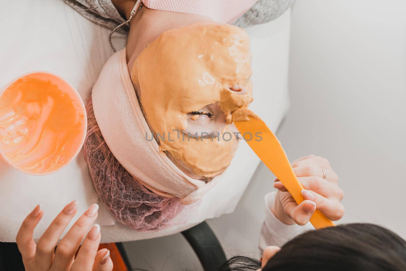 Using a gold mask in cosmetology, a woman at a beautician applying a gold mask on her face. new