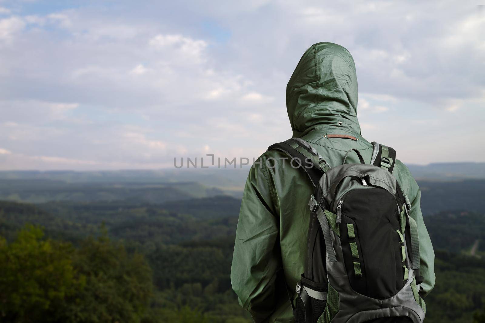 Hiker with backpack standing on top of a mountain and enjoying nature