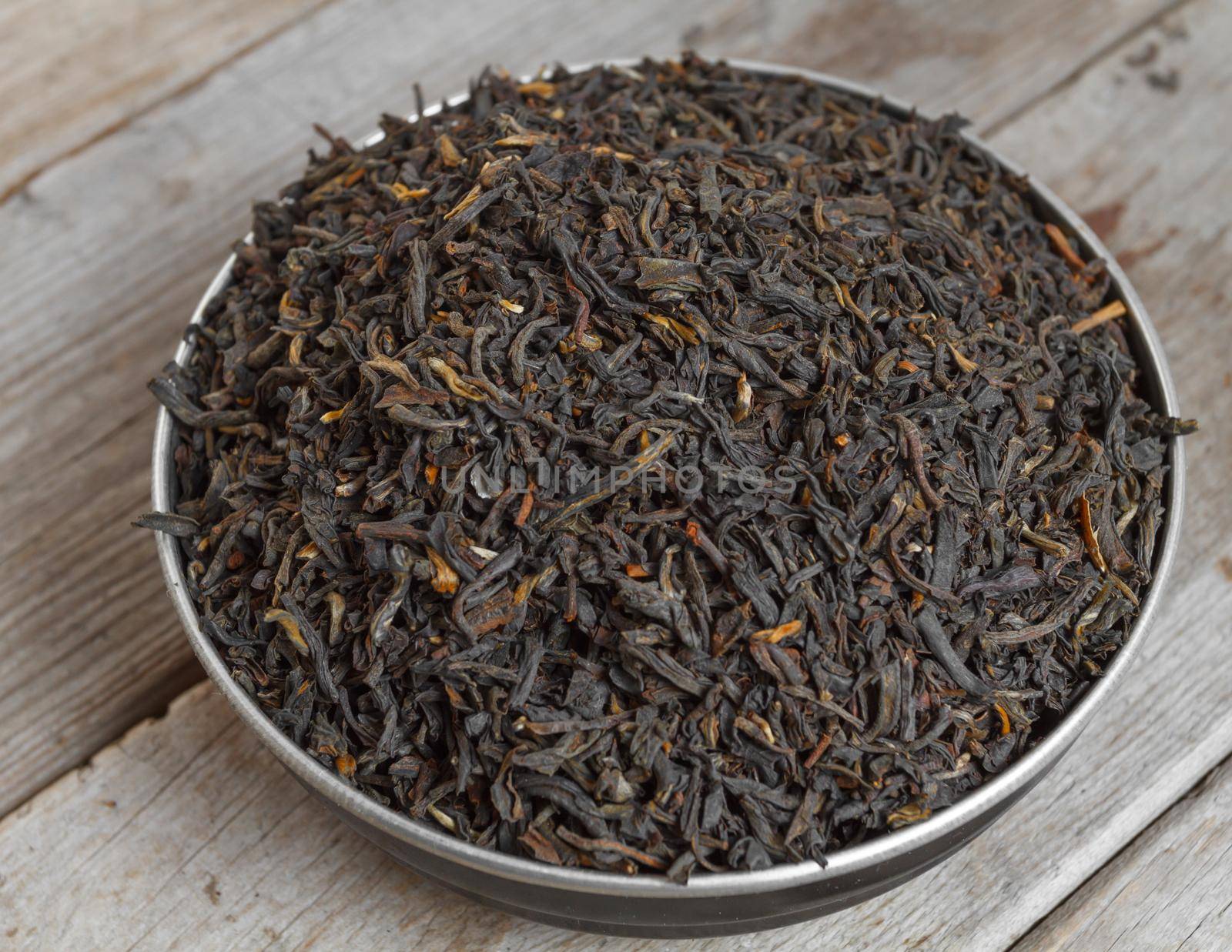 Black leaf tea on a wooden background, top view