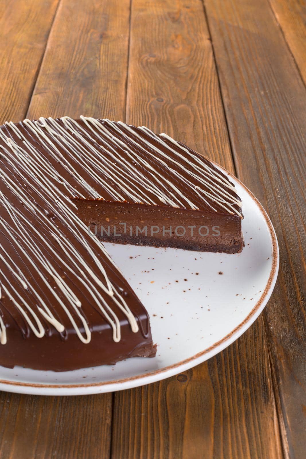 Cut chocolate cake on plate on wooden table close up