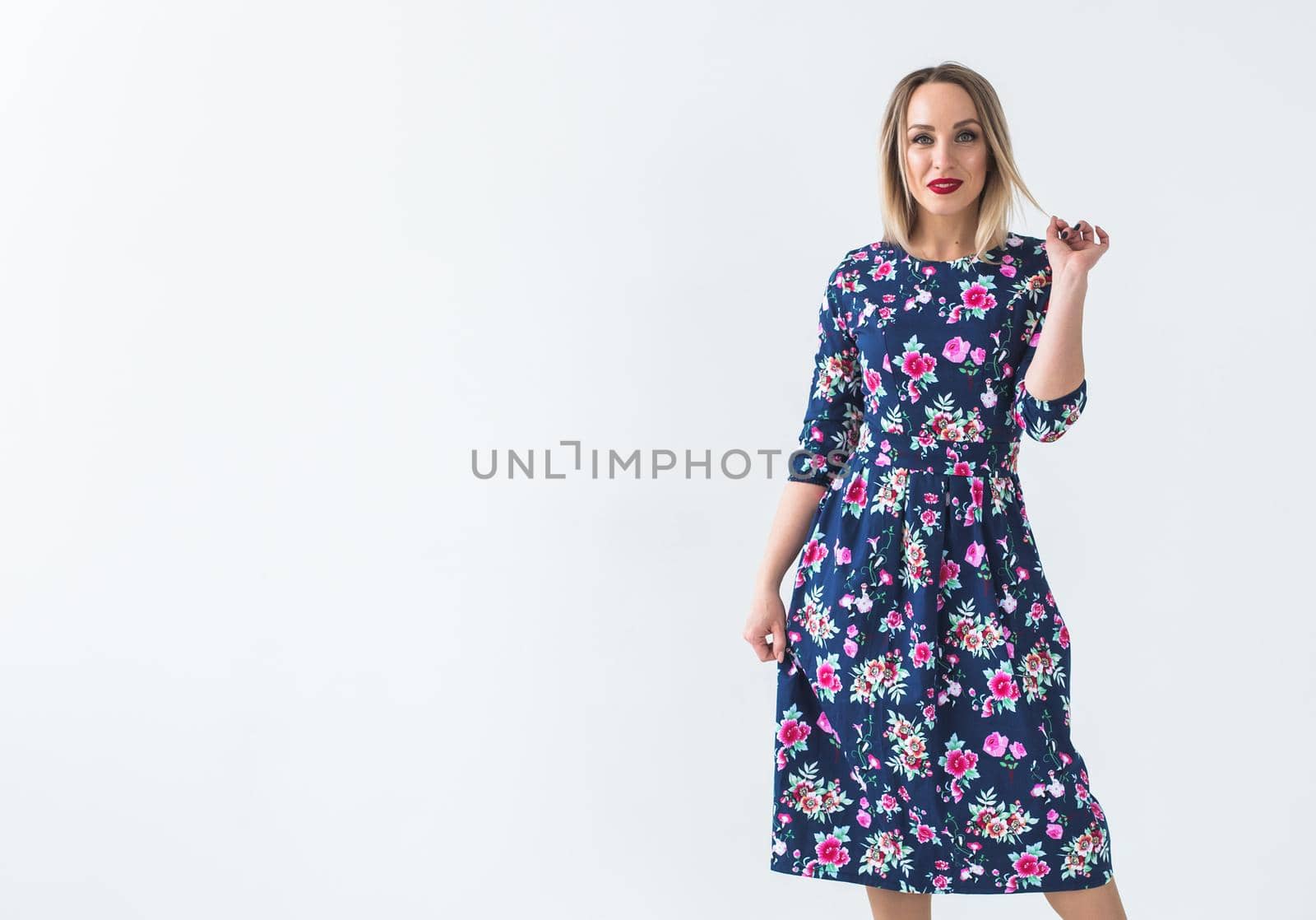 Fashionable young woman in beautiful dress posing at studio. Isolated over white.