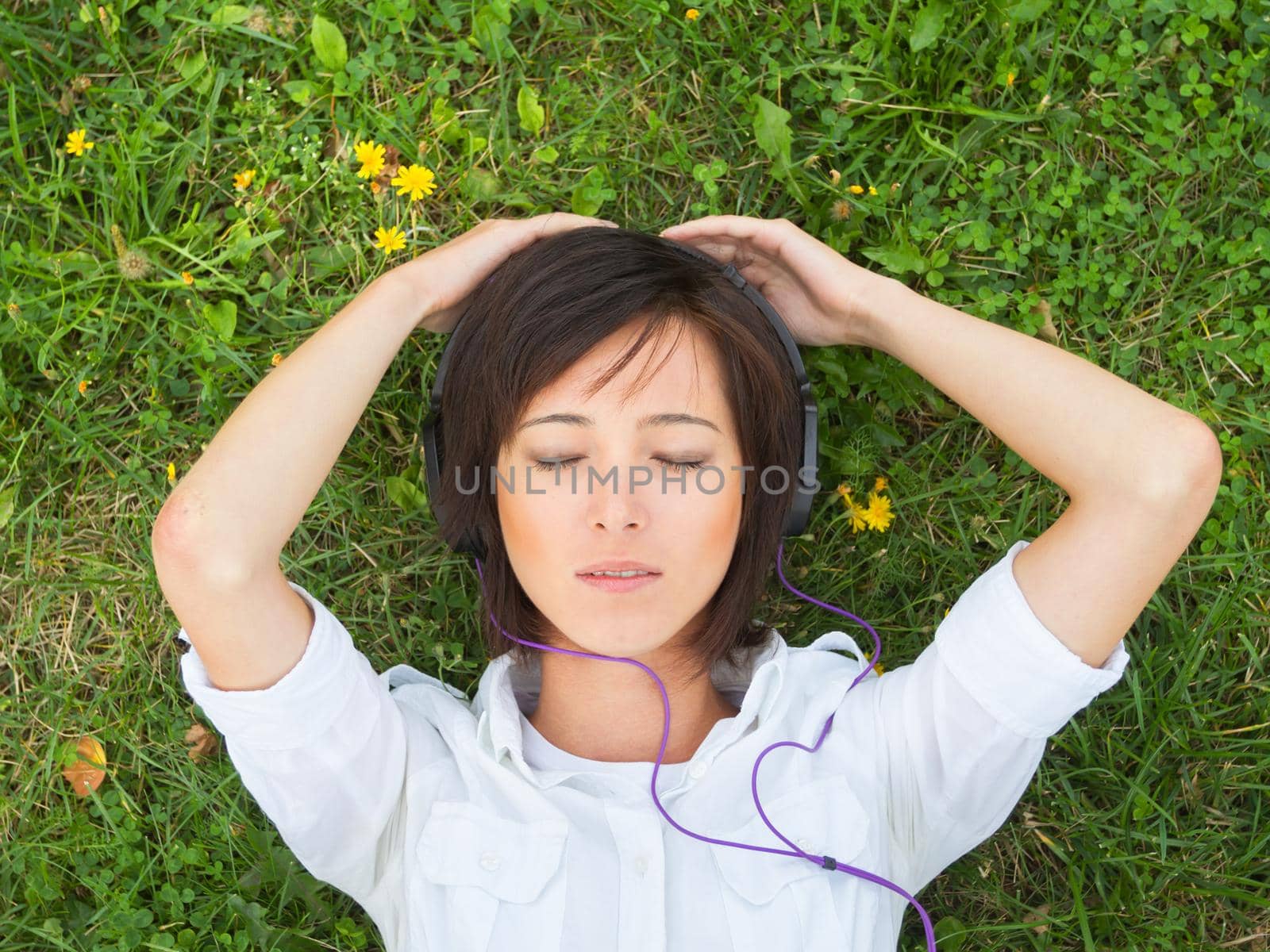 Young woman enjoying the music with closed eyes on a summer meadow