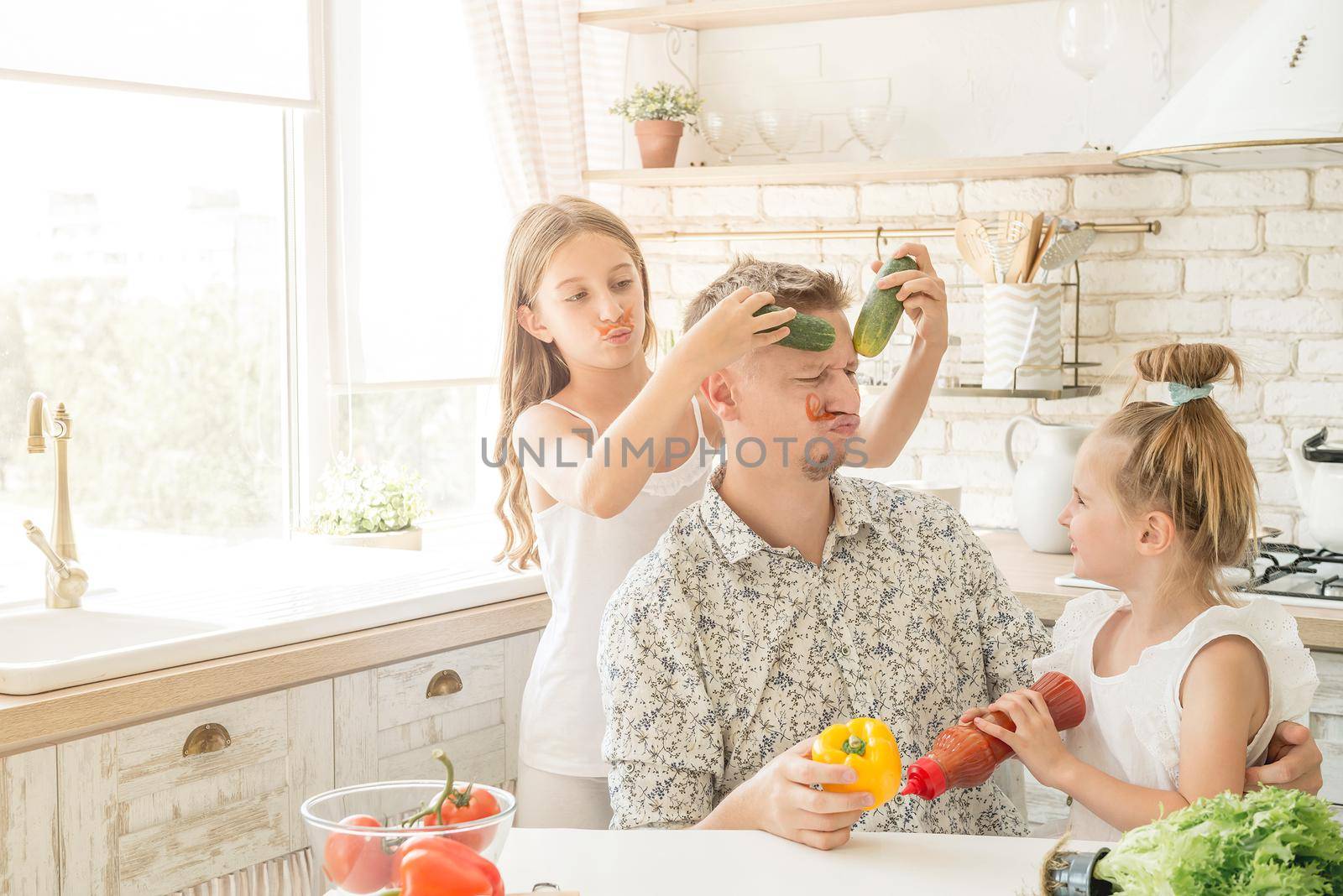 dad with two little daughters have a fun in the kitchen