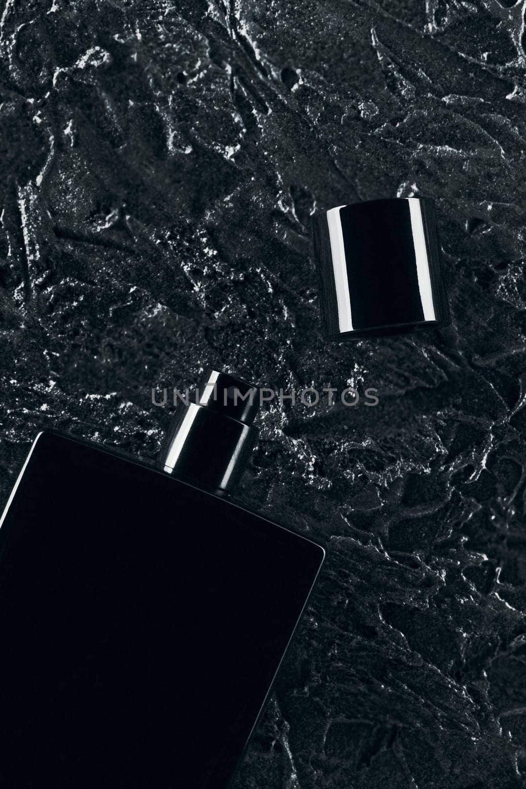 Men's fragrance of perfume or eau de toilette. Promotional photo of a black bottle on a dark background. Layout by SergeyPakulin