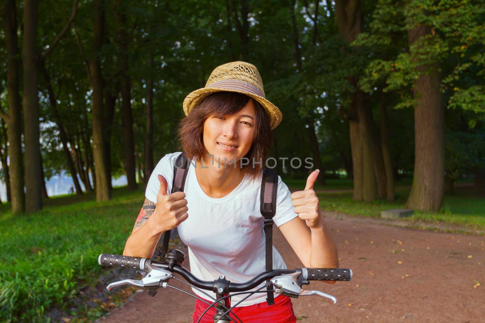 Hipster girl with bicycle shows sign two thumbs up