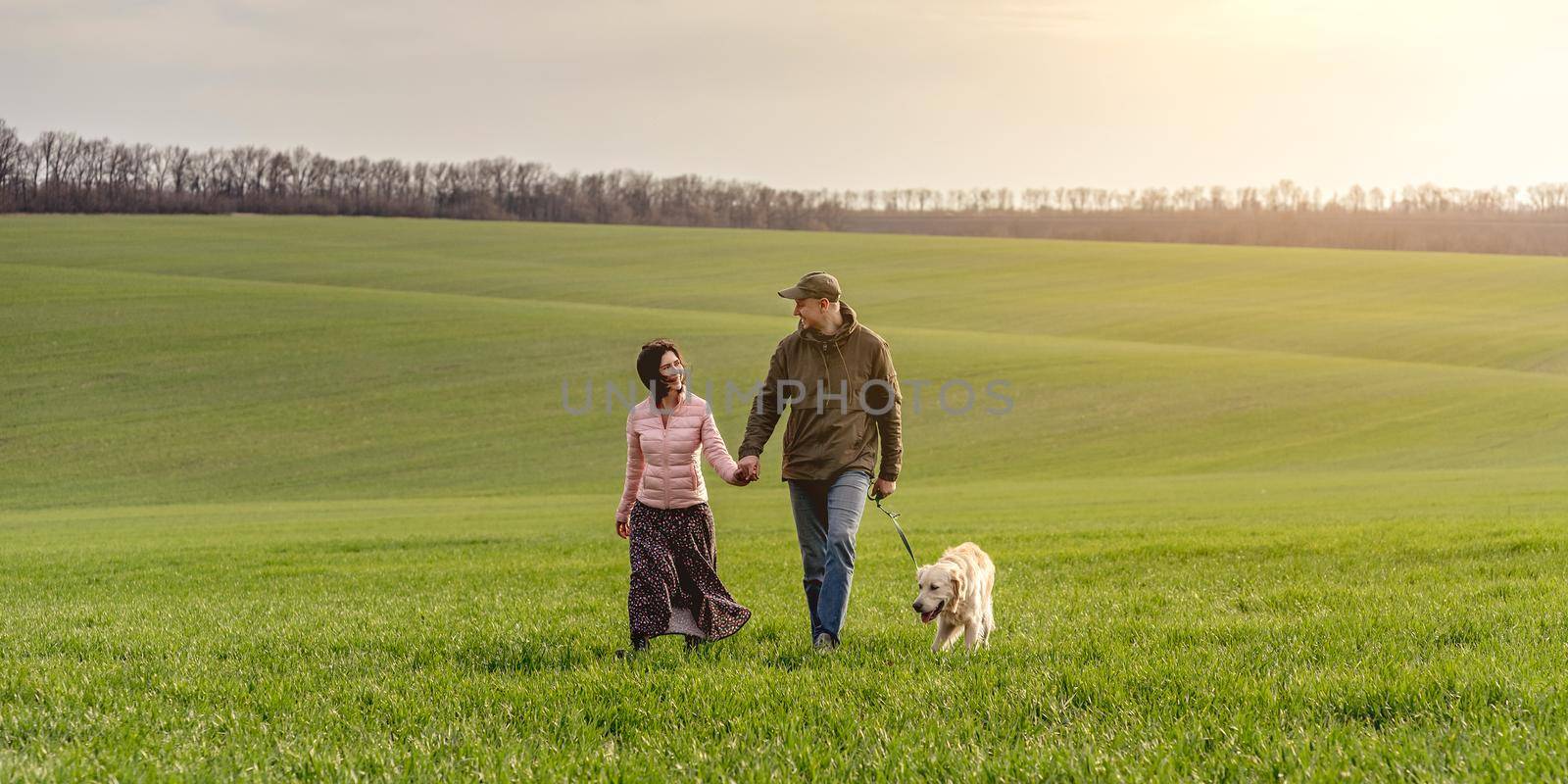 Couple walking dog on spring field by tan4ikk1