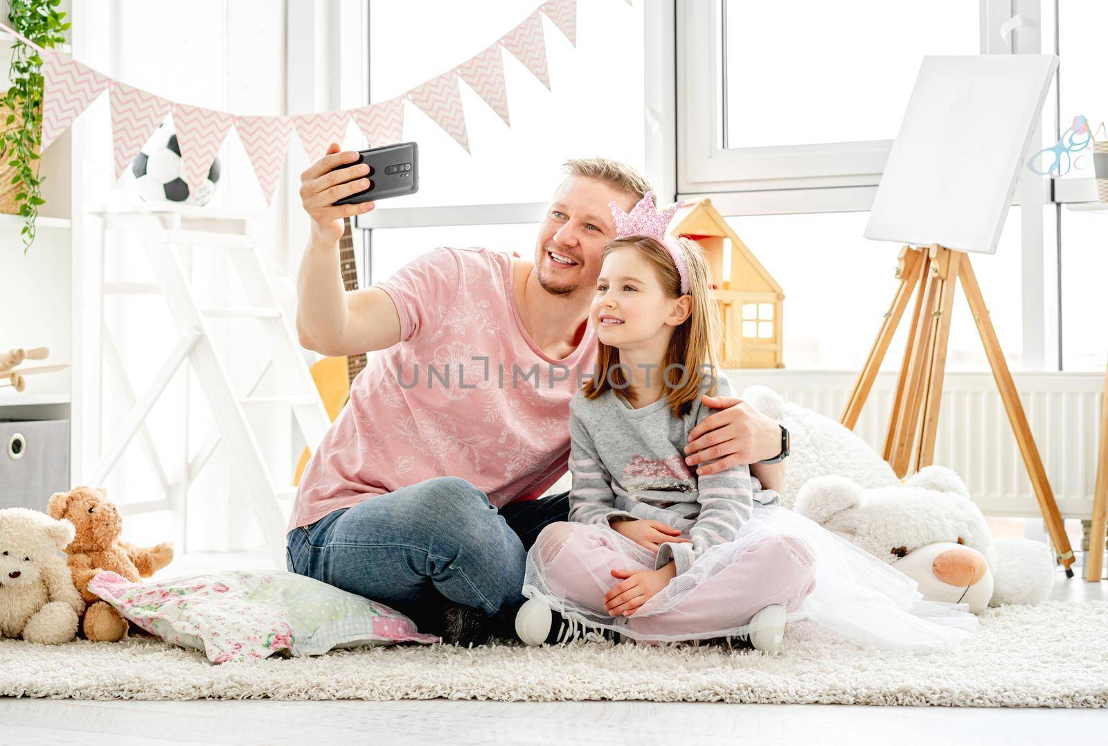 Happy father with cute daughter taking selfie in kids room