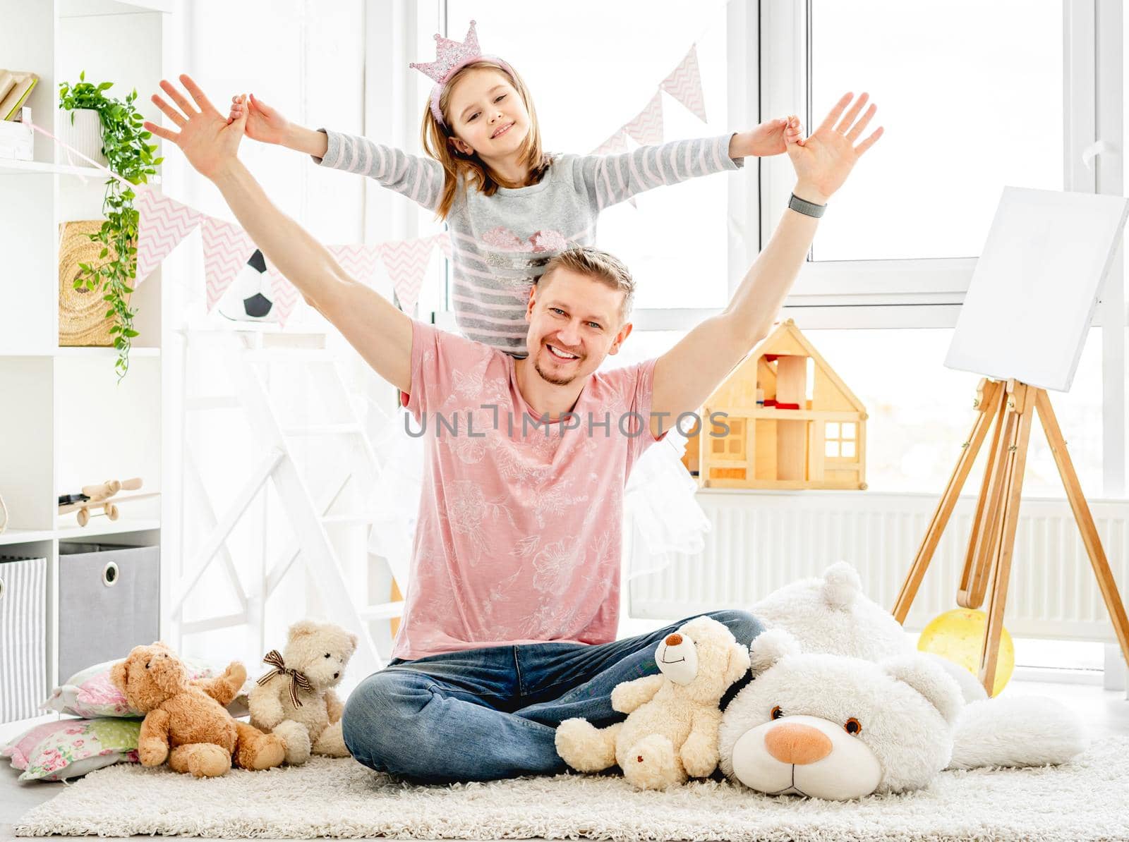 Happy father hugging beautiful little daughter in playroom