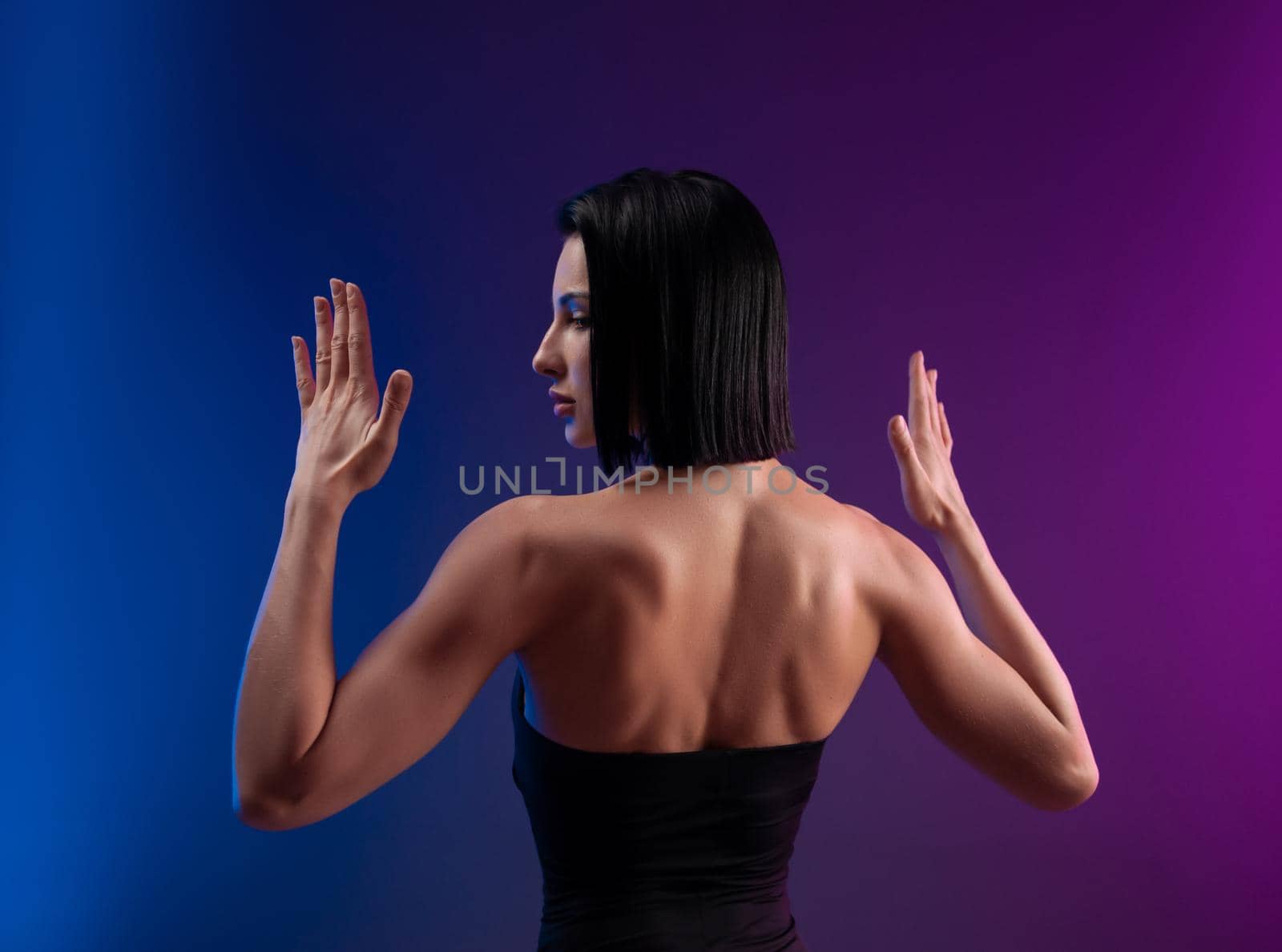 the strong muscular back of a brunette girl on a neon background