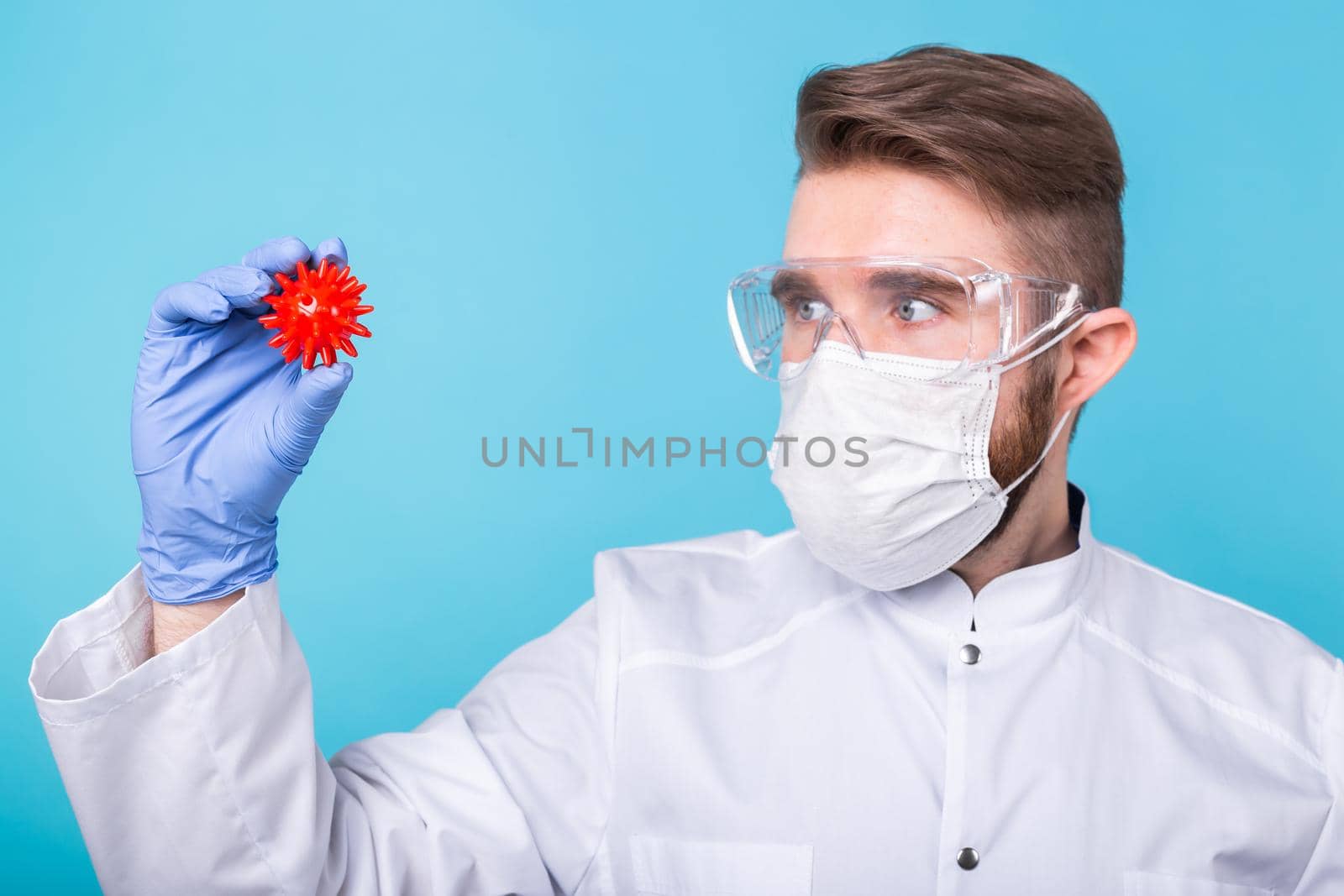 Covid-19, Vaccine development and medicine concept - Man scientist in flu mask and protective gloves holding a model of coronavirus. by Satura86