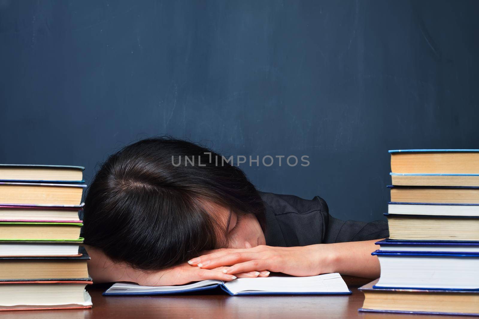 Tired woman lies between stacks of books