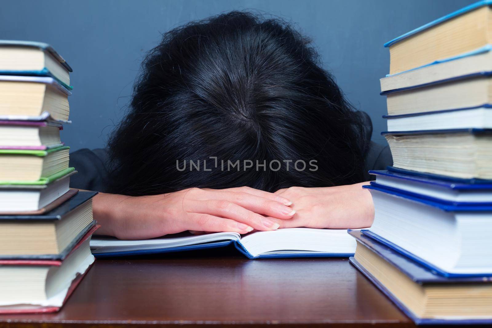 Woman sleeps between stacks of books