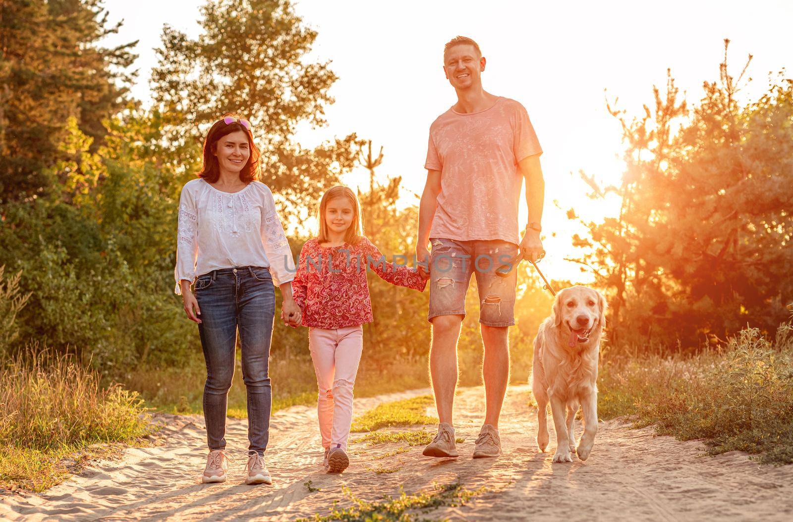 Family with dog walking outdoors at sunset by tan4ikk1