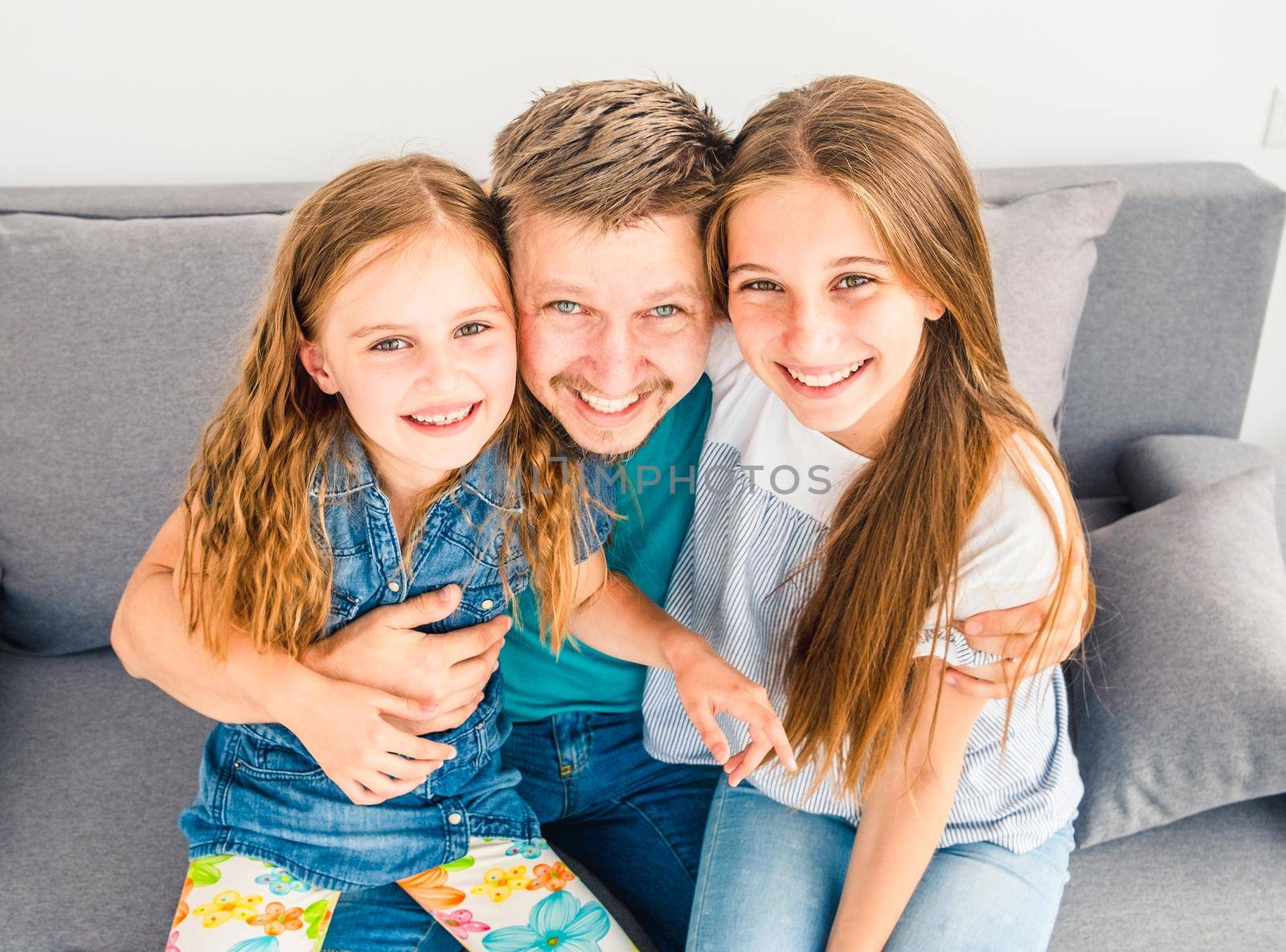 Portrait of happy father with two adorable smiling daughters on the couch
