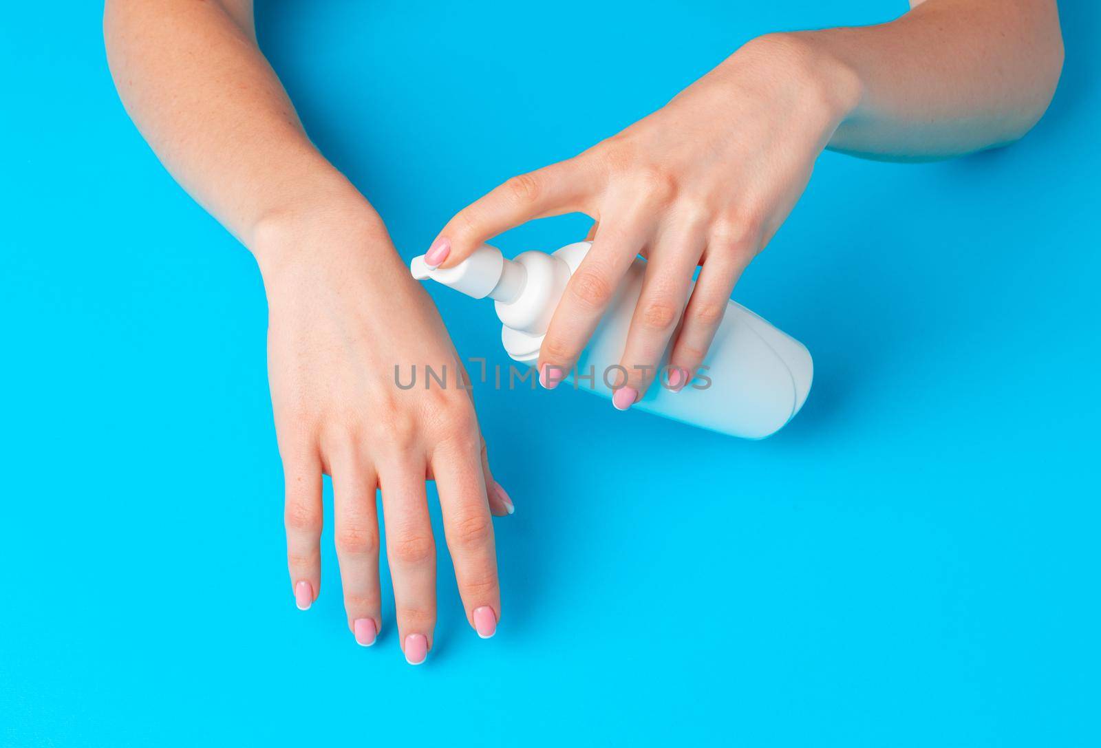 Female hand holding skincare product bottle on blue background
