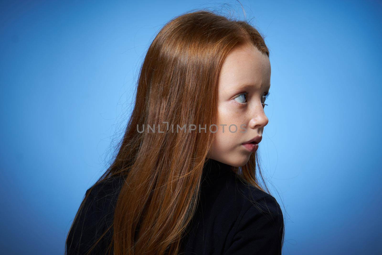 redhead girl with freckles on her face posing close-up blue background. High quality photo