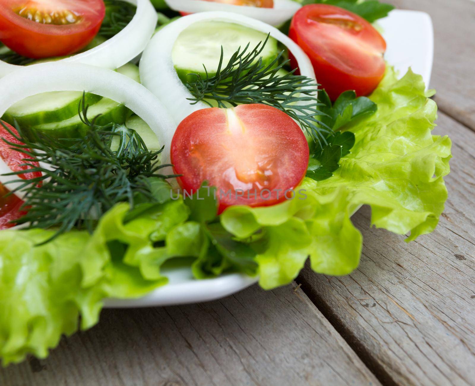 Salad leaves with vegetables on a wooden table