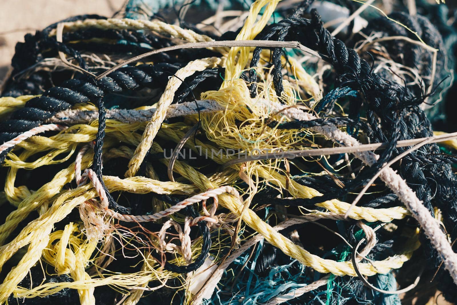 E Close multi colored black white yellow green old fishing twisted cotton ropes heap pile jumble detail. Concept tangle mess mix mishmash maze, environmental protection rubbish, more tones in stock.