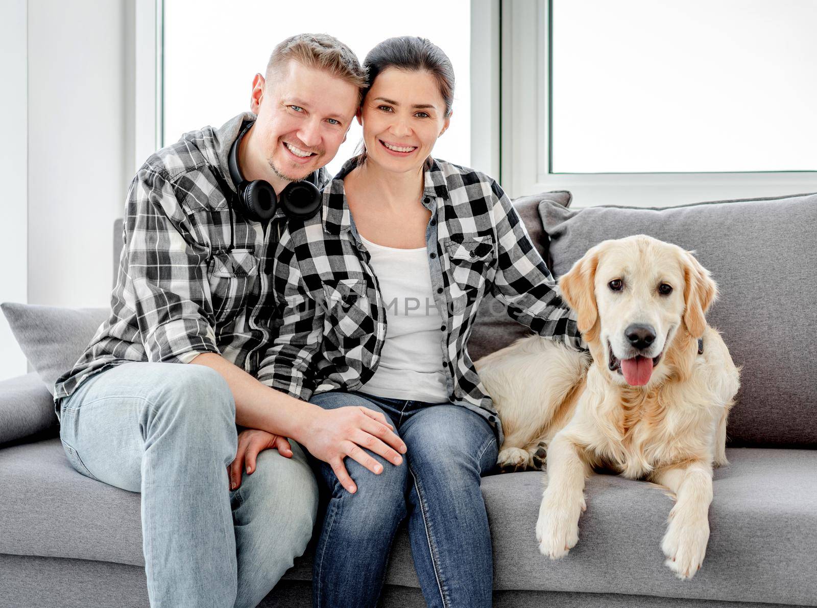 Smiling couple palming golden retriever at home