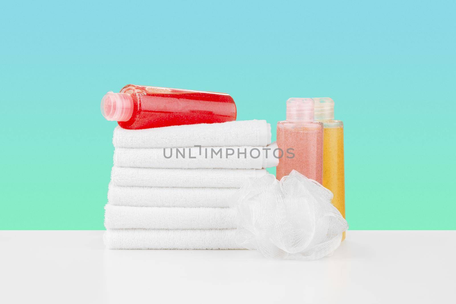 Pile of towels, bottles with shampoo on white table isolated