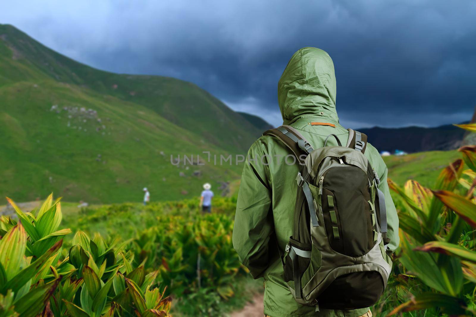 Hiker man walks along a mountain path with a backpack.