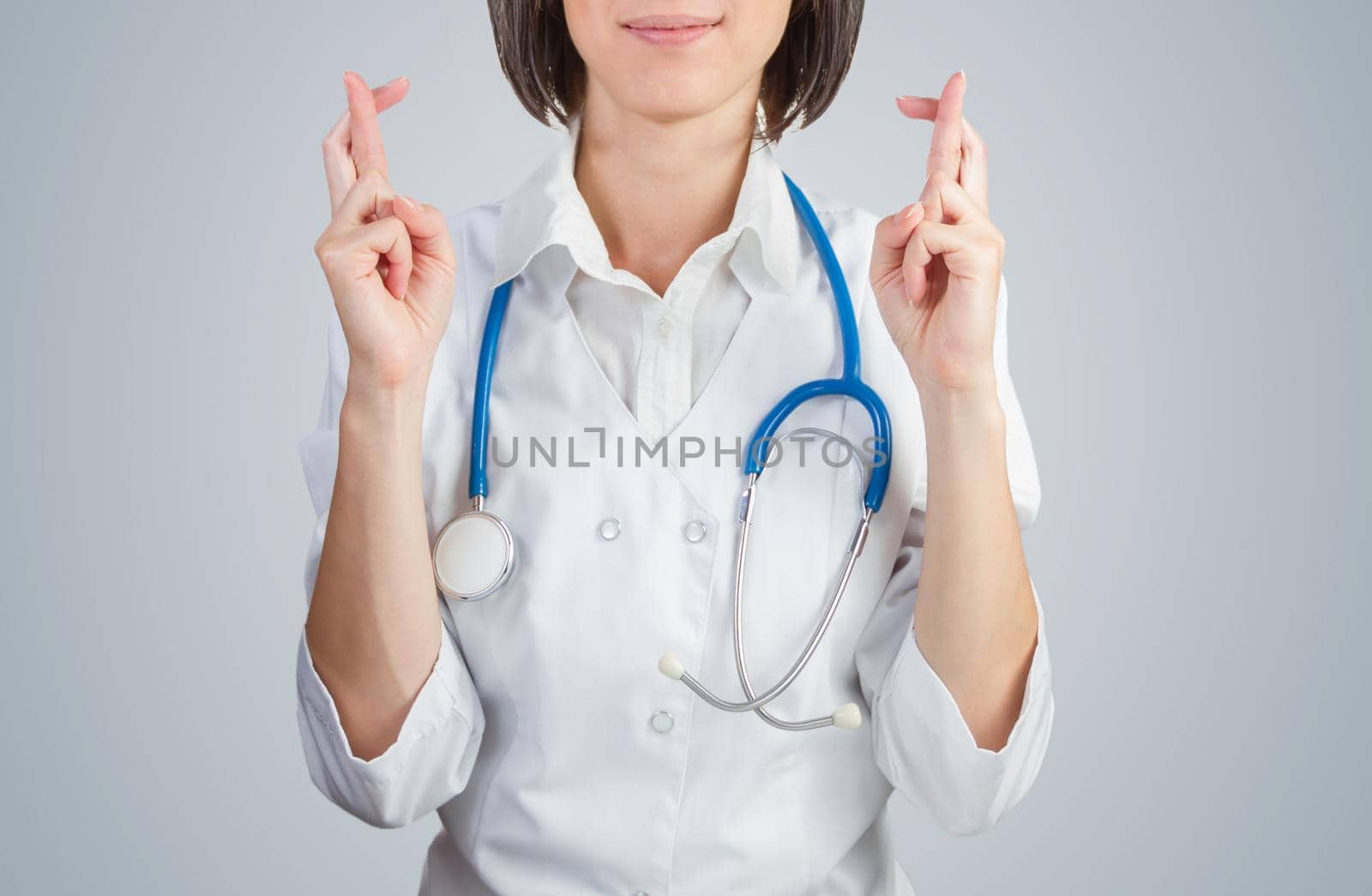 Female doctor crossed her fingers on a blue background